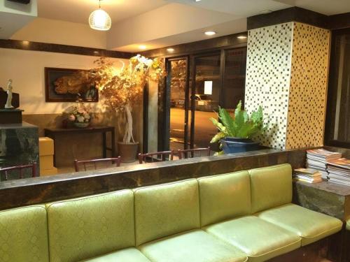 a lobby with a green couch in a room at Numsin Hotel in Ratchaburi