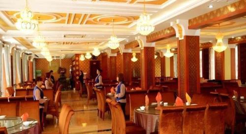 a dining room with people sitting at tables in a restaurant at Dunhuang Dunhe Hotel in Dunhuang