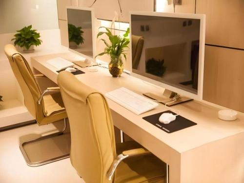 a desk with a computer monitor and yellow chairs at 7 Days Premium Tongliao Train Station Branch in Tongliao