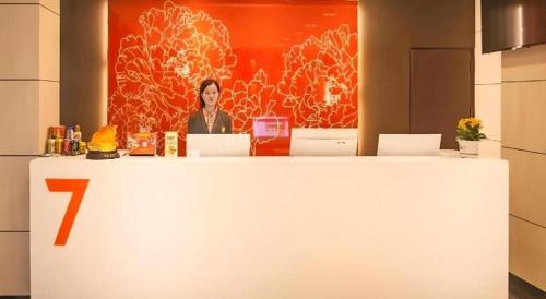 a woman sitting at a counter in a room at 7 Days Premium Tongliao Train Station Branch in Tongliao