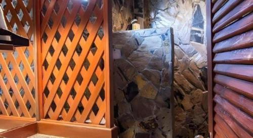 a stone shower in a room with a wooden wall at Tong Hotel in Maha Sarakham