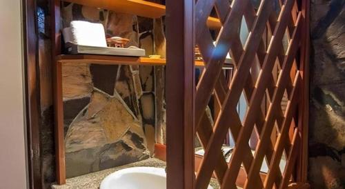 a wooden gate in a bathroom with a stone wall at Tong Hotel in Maha Sarakham