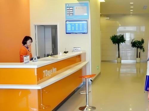 a woman standing at a counter in a hospital lobby at 7 Days Inn Jinan Changqing Jingshi West Road Center in Jinan