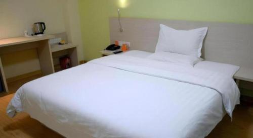 a large white bed in a room with a telephone at 7 Days Inn Jinan Changqing Jingshi West Road Center in Jinan