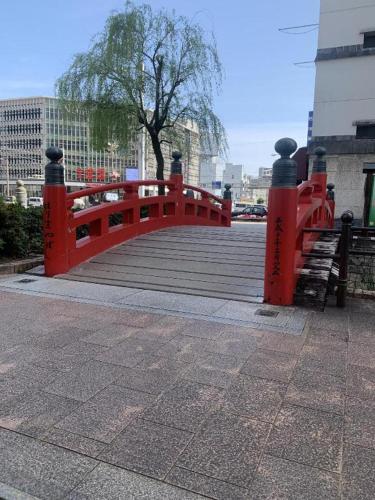 a red bridge over a boardwalk in a city at Hotel Town Nishikigawa in Kochi