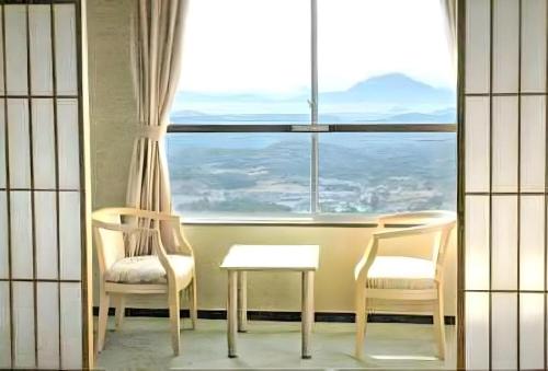 a room with two chairs and a table and a window at Kirishima Onsen Ryokojin Sanso in Kirishima