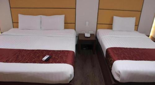 two beds in a hotel room with a remote control between them at Horizon Hotel in Olongapo