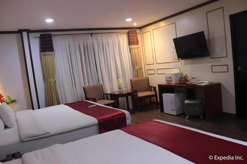 a hotel room with two beds and a desk at Horizon Hotel in Olongapo
