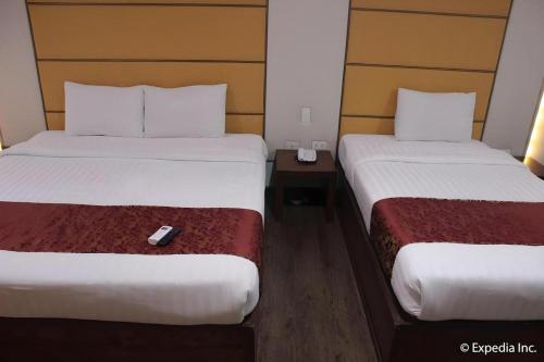 two beds in a hotel room with a remote control between them at Horizon Hotel in Olongapo