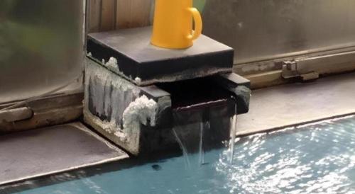 a water fountain with a yellow cup sitting on top at Kakeyu Onsen Hotel Kameya in Ueda