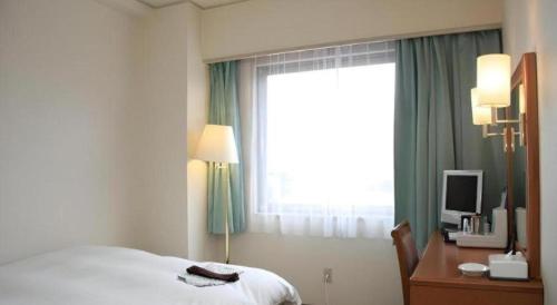 a hotel room with a bed and a desk and a window at Hotel Royal Hill Fukuchiyama and Spa in Fukuchiyama