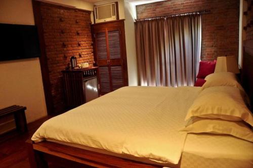 a bedroom with a white bed with a brick wall at Mango Valley Hotel in Olongapo