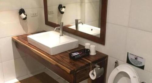 a bathroom with a sink and a mirror and a toilet at Mango Valley Hotel in Olongapo