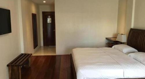 a bedroom with a white bed and a television at Mango Valley Hotel in Olongapo