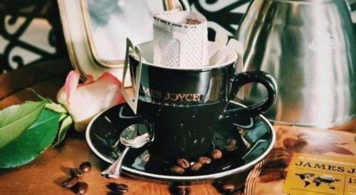 a black coffee cup on a plate with coffee beans at James Joyce Coffetel Chengdu Jianshe Road Dongjiao Jiyi Square in Chengdu