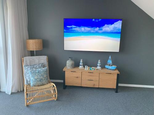 a room with a chair and a tv on a wall at Corrigans Beach View Apartment 211 in Batehaven
