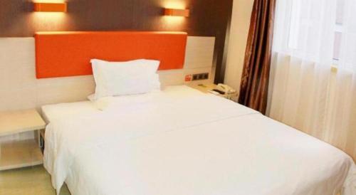 a white bed with an orange headboard in a room at 7 Days Premium Beijing Dabaotai Metro Station Luhua Road in Beijing