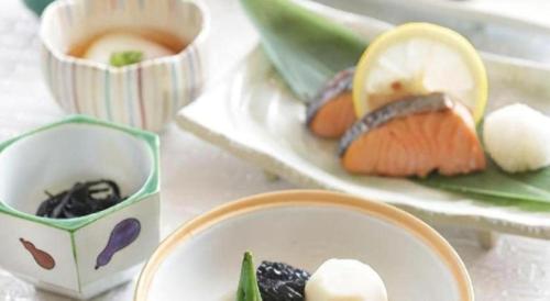 a table with a plate of sushi and a bowl of food at Hotel Grand Shinonome in Tsukuba