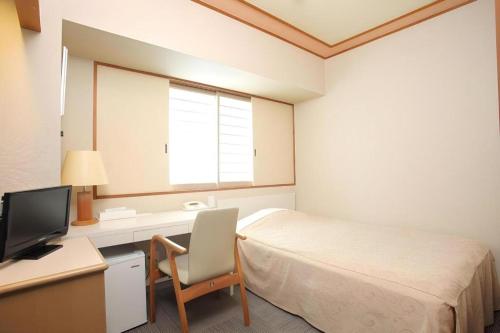 a bedroom with a bed and a desk and a television at Hotel Grand Shinonome in Tsukuba