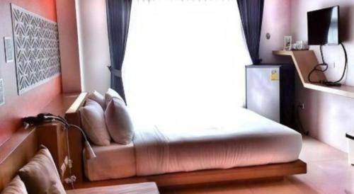 a bed in a room with a window at Tonkok Hotel in Chiang Rai