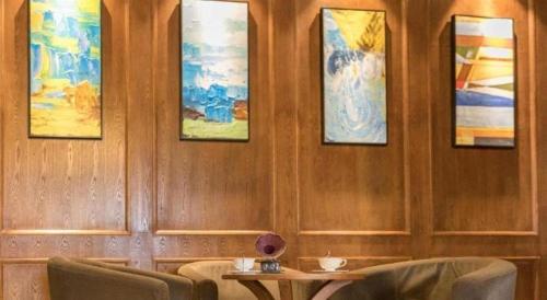 a room with chairs and paintings on the wall at James Joyce Coffetel Qufu Tourist Center Gulou Street Sankong Scenic Spot in Jining
