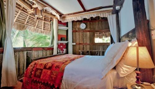 a bedroom with a bed in a room with a window at Utupoa in Matemwe