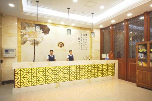 two people standing at a counter in a restaurant at Li An Hotel Shantou Xiashan Central Bus Station Branch in Shantou