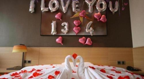 a bedroom with two swans and a sign that reads love you at IU Hotel Zhangye High-Speed Railway Station in Zhangye