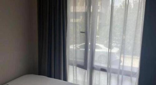 a bedroom with a window with a white curtain at Magnotel Harbin Songbei Wanda Wenlvcheng in Harbin