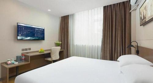 a hotel room with a bed and a desk and a monitor at Jinjiang Inn Select Tianjin Xiaobailou Metro Station in Tianjin