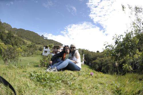 two people sitting in the grass in a field at Jardin Colibri RNT 33633 in Guatavita