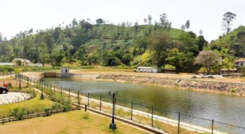 a body of water with a fence next to a river at Talawakele Rest House in Nuwara Eliya