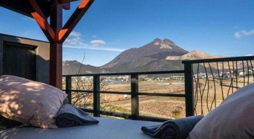 a bed with pillows on a balcony with a view of a mountain at Yufuin Luxury Villa -zakuro- in Yufuin