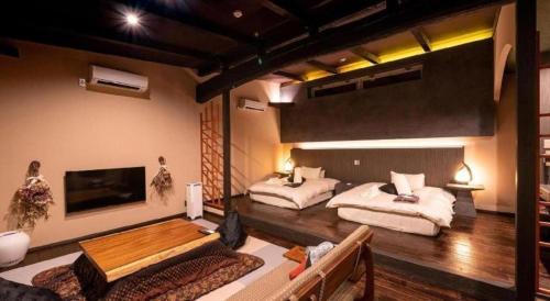 a large room with two beds and a television at Yufuin Luxury Villa -zakuro- in Yufuin