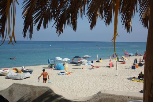 a group of people on a beach with the ocean at Villaggio Camping Fiorina in Capo Vaticano