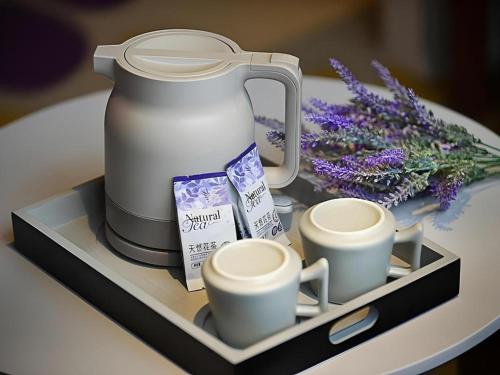 un vassoio con due tazze da caffè e fiori su un tavolo di Lavande Hotel·Yichun Wanda, High Speed Railway Station a Yichun