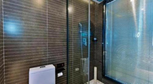 a bathroom with a toilet and a glass shower at Xana Hotelle Chengdou Xindu Sanhechang Metro Station in Chengdu