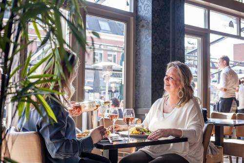 Dos mujeres sentadas en una mesa en un restaurante bebiendo vino en Stravinsky Slapen, en Hengelo