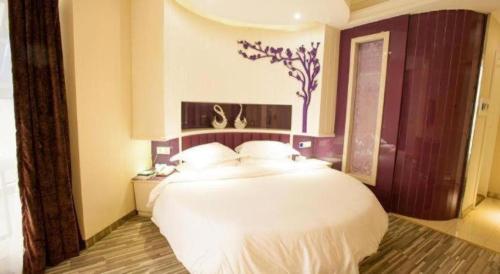 a bedroom with a large white bed and a window at City Comfort Inn Wuhan Ikea in Wuhan