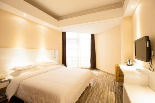 a hotel room with a bed and a flat screen tv at City Comfort Inn Wuhan Ikea in Wuhan