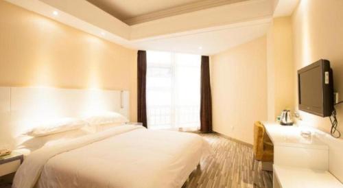 a hotel room with a bed and a tv at City Comfort Inn Wuhan Ikea in Wuhan