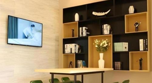 a living room with a table and a tv on a wall at City Comfort Inn Wuhan Ikea in Wuhan