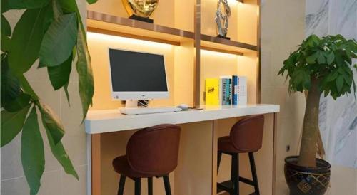 a desk with a computer and two chairs at Borrman Hotel Zhanjiang Shimao Building High-speed Railway Station in Zhanjiang