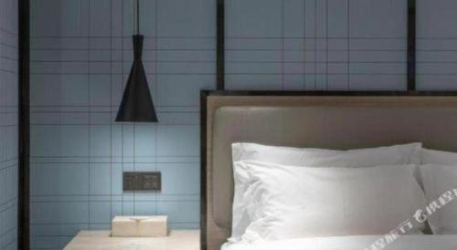 a bed with white sheets and a blue wall at Echarm Hotel Zibo Gaoqing Zhongcheng Inernational in Zibo