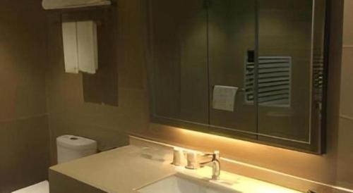 a bathroom with a sink and a mirror and a toilet at City Comfort Inn Yi'Ning Jichang Road Shanghaicheng in Kipekyüzi