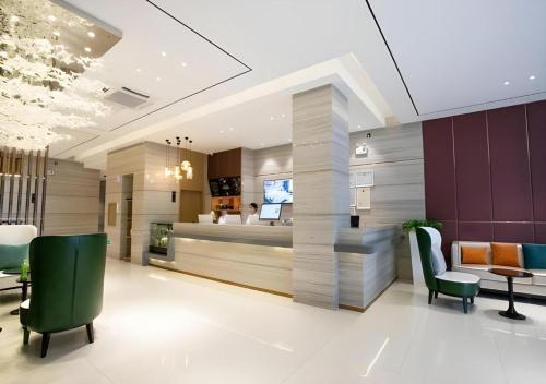a lobby with green chairs and a reception desk at City Comfort Inn Beiliu Yongfeng Plaza Chengnan Bus Station in Yulin