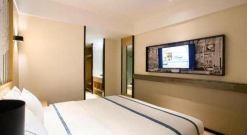 a hotel room with a bed and a flat screen tv at City Comfort Inn Beiliu Yongfeng Plaza Chengnan Bus Station in Yulin