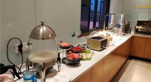 a kitchen counter with a mixer and flowers on it at City Comfort Inn Yingcheng Railway Station Shanghe Square in Xiaogan