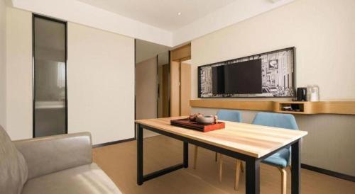 a room with a table with chairs and a tv at City Comfort Inn Liuzhou Wuling Liutai Road in Liuzhou