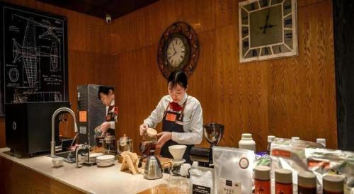 two people in a kitchen preparing food on a counter at James Joyce Coffetel Luoyang Longmen High-speed Railway Station Baolong Plaza in Luoyang